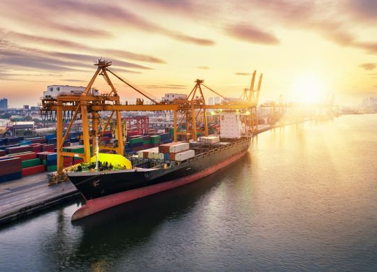 Aerial view of business port with Shore crane loading containers in freight ship. Container ship in import export and business logistics with crane and Shipping cargo. International transportation and Business logistics concept.